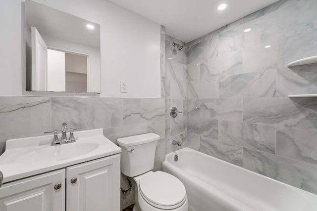 full bathroom with vanity, toilet, tiled shower / bath combo, and tile walls