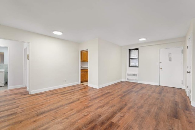 spare room with radiator heating unit and hardwood / wood-style floors