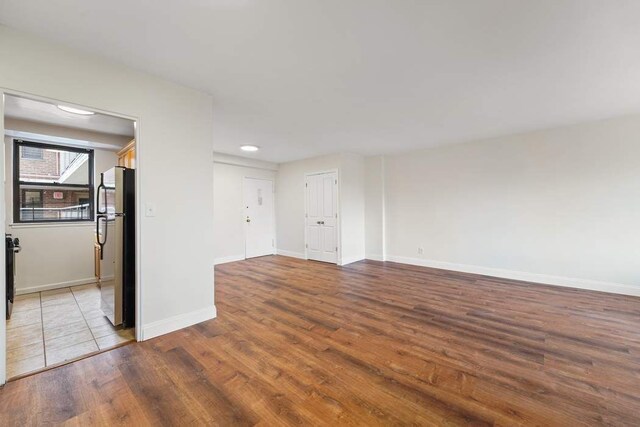 empty room with plenty of natural light, radiator, and hardwood / wood-style floors