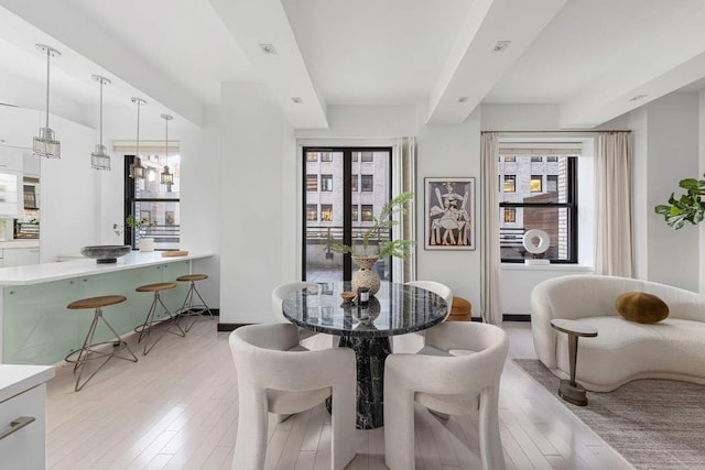 dining space with beamed ceiling and light hardwood / wood-style flooring