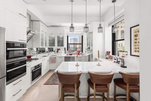 20 Pine St Unit 3001, New York City, NY 10005 - kitchen with a kitchen bar, white cabinetry, hanging light fixtures, and appliances with stainless steel finishes