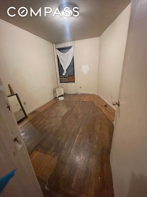 unfurnished room featuring wood finished floors and radiator