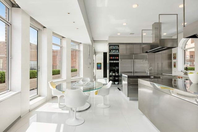 kitchen with built in refrigerator, island exhaust hood, and light tile patterned flooring