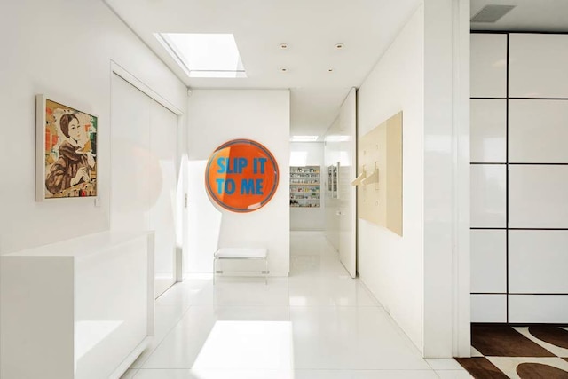 hallway with tile patterned flooring and a skylight