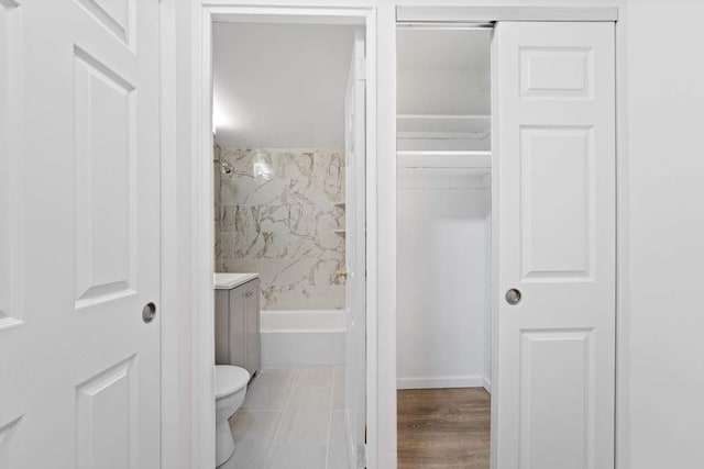 full bathroom with tiled shower / bath, vanity, and toilet