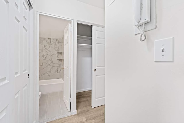 bathroom featuring tiled shower / bath combo, hardwood / wood-style floors, and toilet