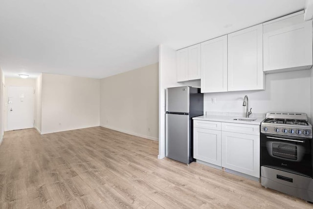 kitchen featuring appliances with stainless steel finishes, sink, light hardwood / wood-style flooring, and white cabinets