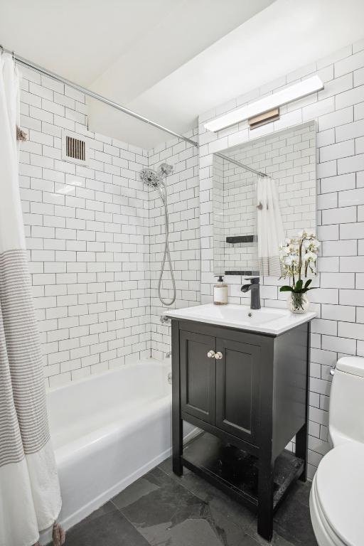 full bathroom featuring shower / bath combo, toilet, tile walls, and vanity