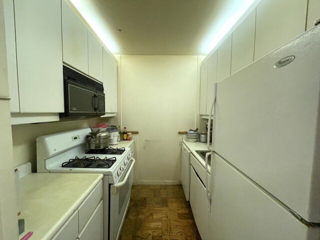 kitchen with white appliances, white cabinetry, and dark parquet flooring