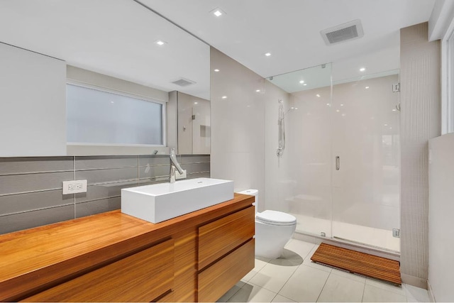 bathroom with tile patterned floors, toilet, tasteful backsplash, vanity, and a shower with door