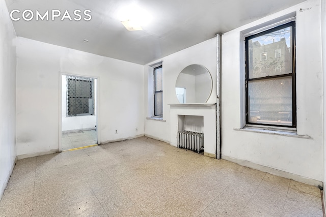 unfurnished room featuring baseboards, radiator heating unit, and tile patterned floors