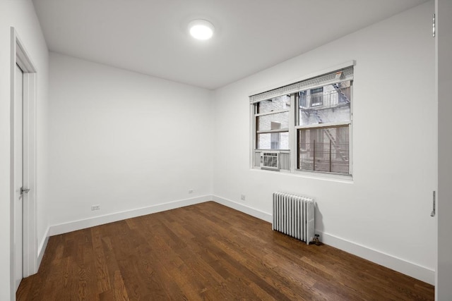 spare room featuring radiator and dark hardwood / wood-style flooring