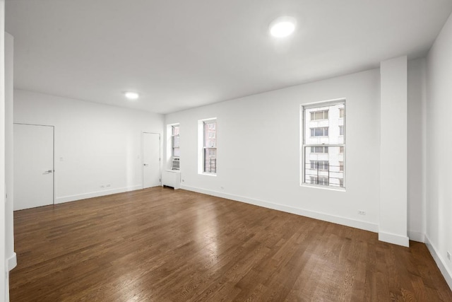 spare room featuring cooling unit and dark hardwood / wood-style floors