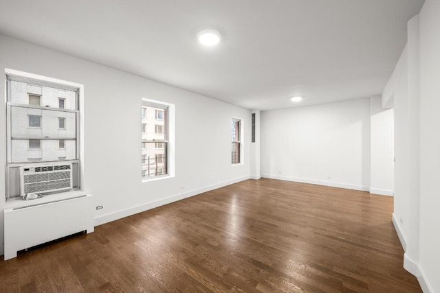 unfurnished room featuring cooling unit, dark hardwood / wood-style floors, and radiator