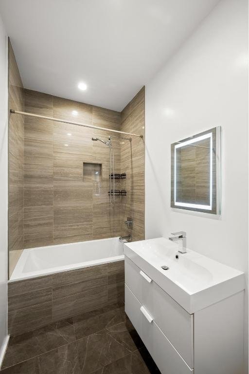 bathroom with tiled shower / bath combo and vanity