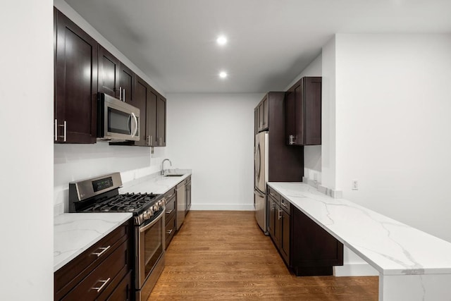 kitchen featuring appliances with stainless steel finishes, sink, light stone counters, and light hardwood / wood-style floors