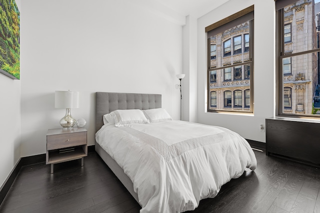 bedroom with dark wood-type flooring and baseboards