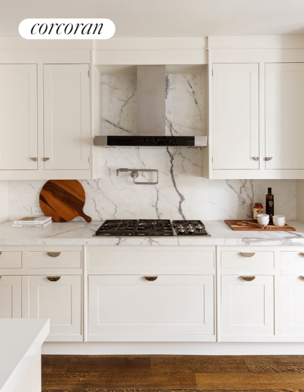 kitchen with light countertops, wall chimney exhaust hood, and white cabinetry