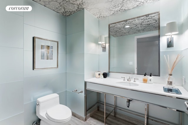 bathroom featuring vanity, tile walls, and toilet