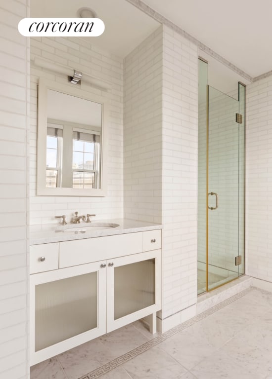 full bath with a stall shower, vanity, and tile walls