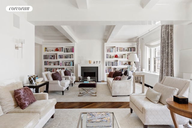 living room featuring built in shelves, wood-type flooring, and beamed ceiling