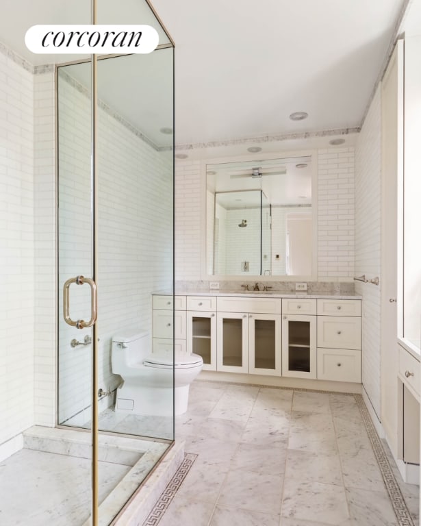 full bath with tile walls, a shower stall, vanity, and toilet