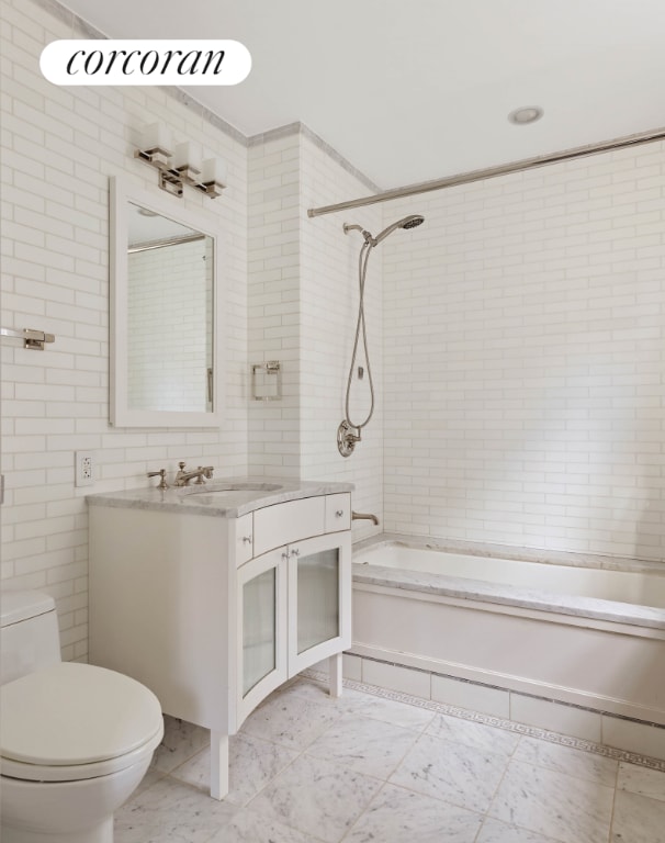 bathroom with tile walls, shower / bathing tub combination, vanity, and toilet