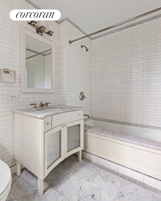 bathroom with shower / bath combination, toilet, tile walls, and vanity