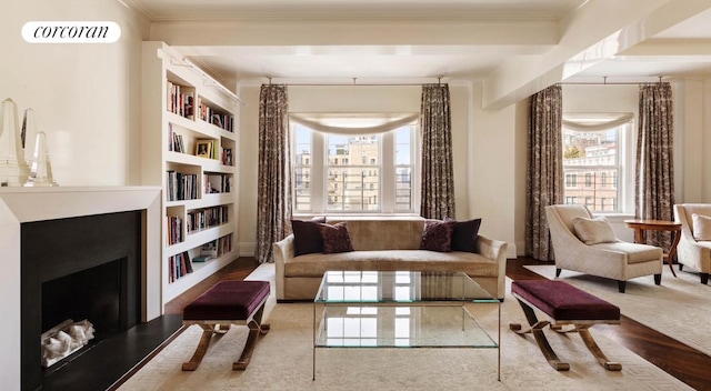 sitting room featuring a fireplace with raised hearth, built in shelves, ornamental molding, and visible vents