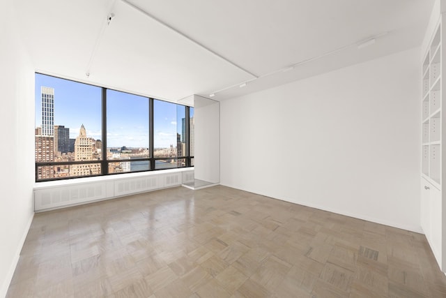 unfurnished room featuring a view of city and baseboards