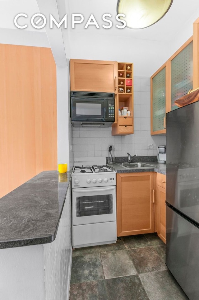 kitchen featuring white gas range oven, glass insert cabinets, freestanding refrigerator, a peninsula, and black microwave