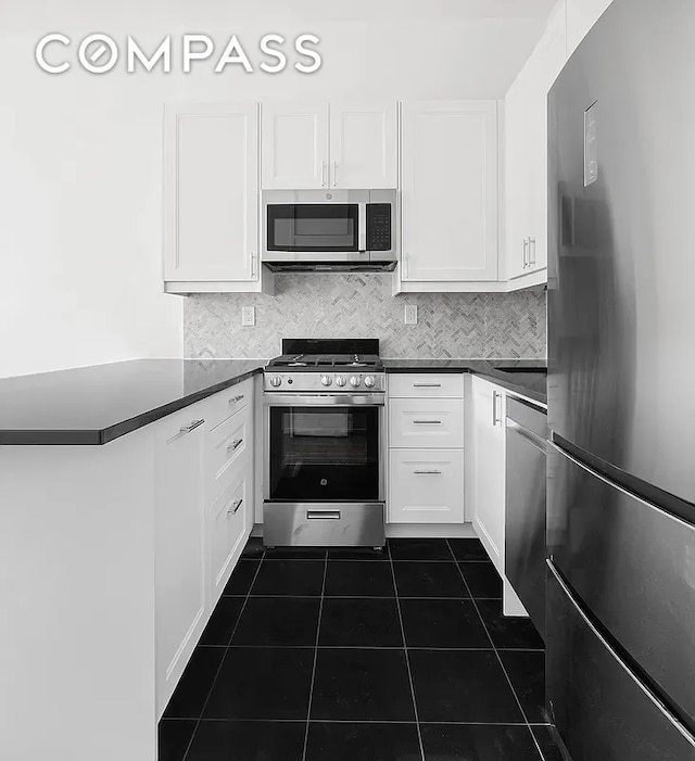 kitchen featuring stainless steel appliances, dark countertops, and white cabinetry