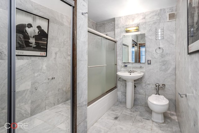 full bathroom featuring sink, tile walls, shower / bath combination with glass door, and toilet