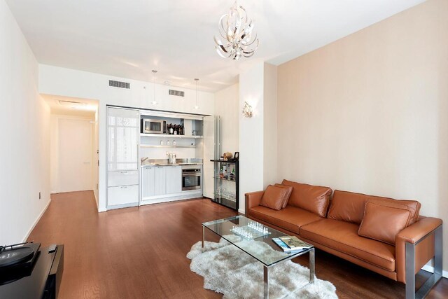 living room featuring dark wood-type flooring and a notable chandelier