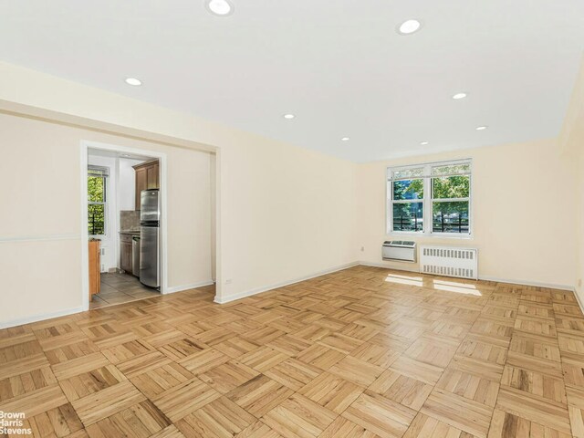 empty room with baseboards, recessed lighting, heating unit, and radiator