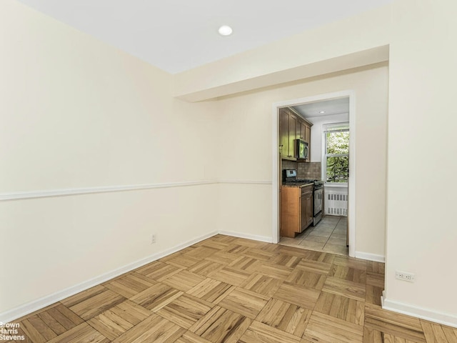 spare room with radiator heating unit, baseboards, and recessed lighting