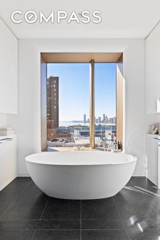 full bath with a view of city, a freestanding bath, and granite finish floor