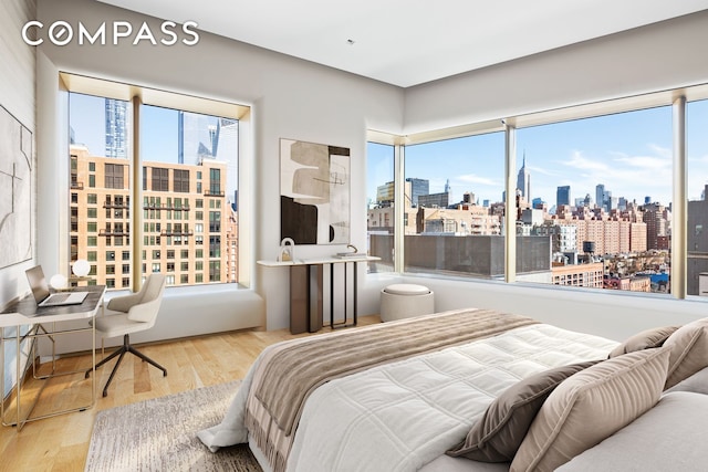 bedroom with a view of city, multiple windows, and wood finished floors