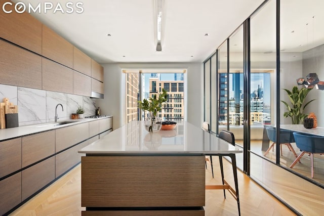 kitchen with sink, decorative backsplash, light parquet flooring, and a kitchen island