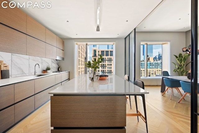 kitchen with backsplash, light parquet flooring, a kitchen island, and plenty of natural light