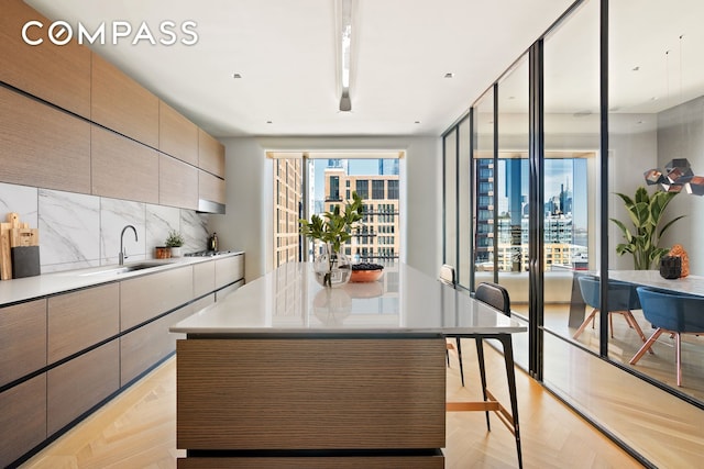 kitchen featuring light countertops, a sink, backsplash, and modern cabinets