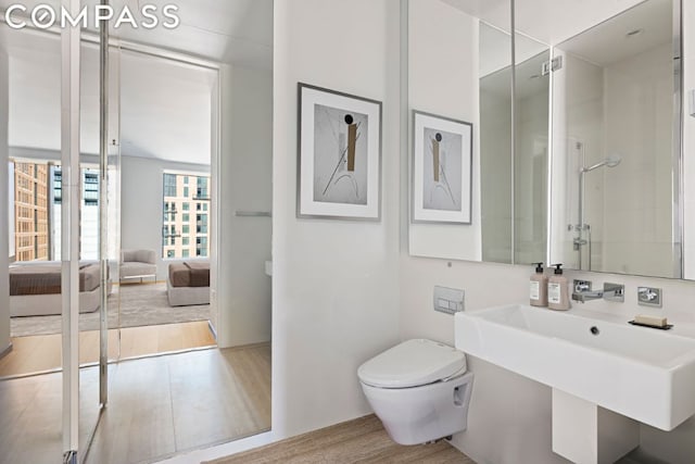 bathroom featuring sink, hardwood / wood-style flooring, toilet, and a shower