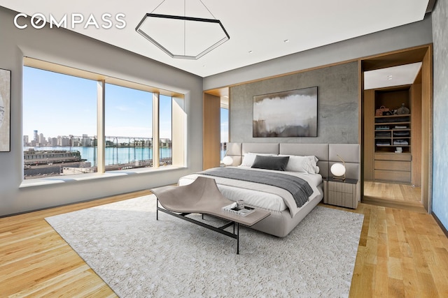 bedroom featuring a view of city, a water view, and wood finished floors