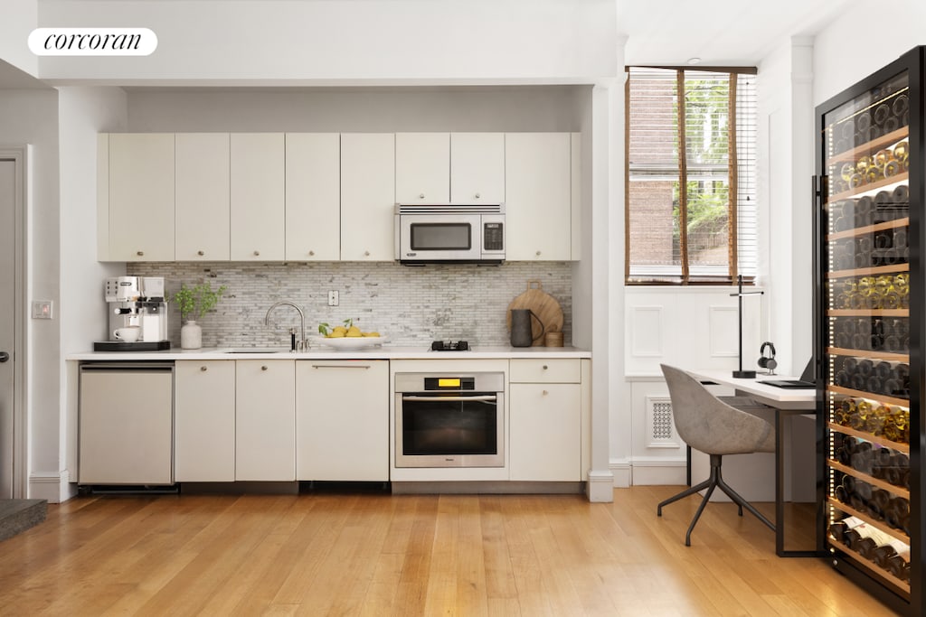 kitchen featuring sink, stainless steel oven, dishwashing machine, decorative backsplash, and white cabinets