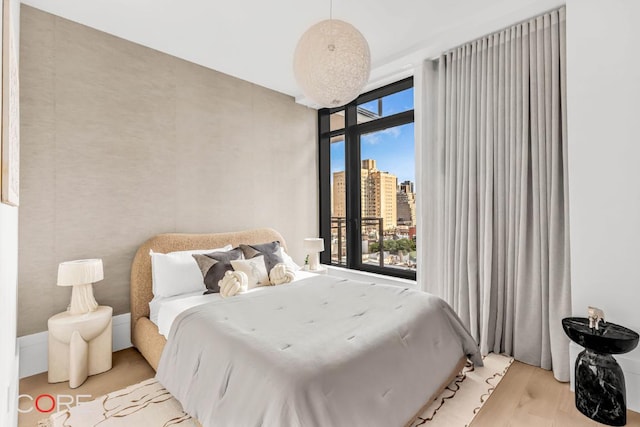 bedroom with floor to ceiling windows and light hardwood / wood-style flooring