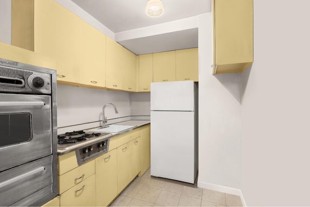 kitchen with gas stovetop, oven, sink, and white fridge