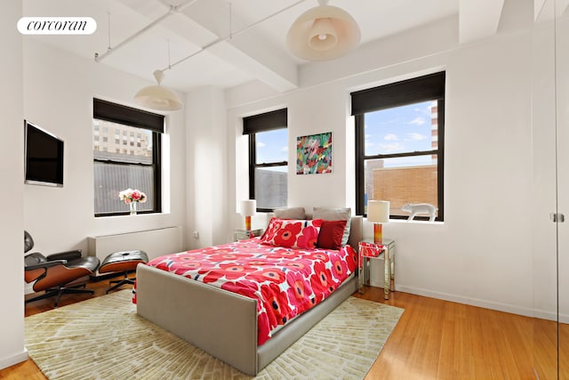 bedroom with visible vents, beamed ceiling, baseboards, and wood finished floors