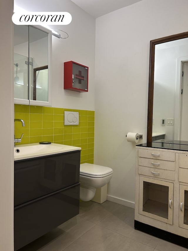 full bathroom with tile patterned floors, a shower with shower door, toilet, tile walls, and vanity