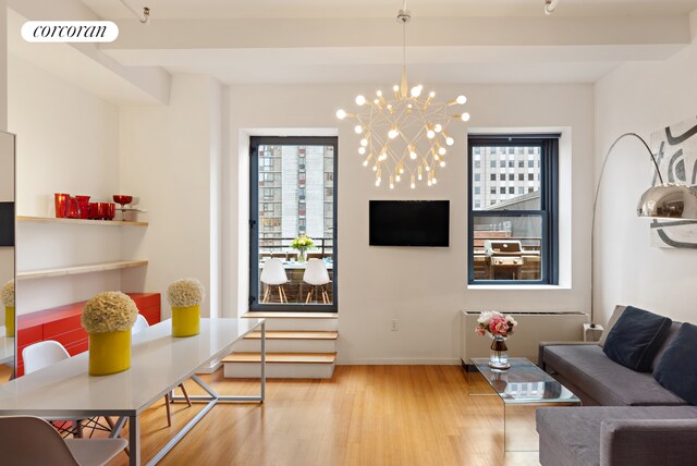 living room with a notable chandelier, visible vents, baseboards, and wood finished floors