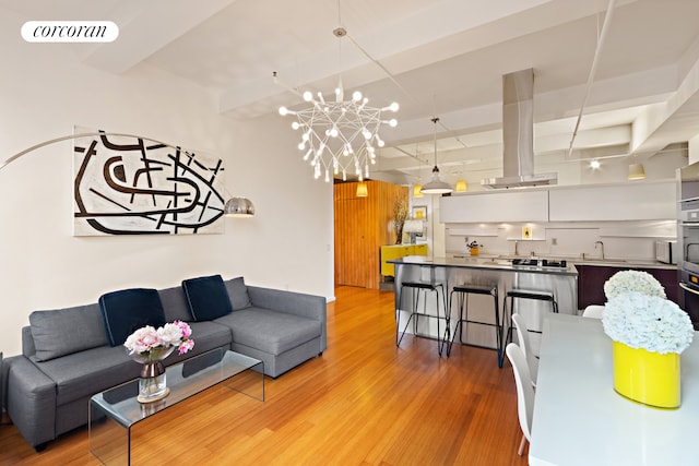 living room with light wood-type flooring, a notable chandelier, and visible vents